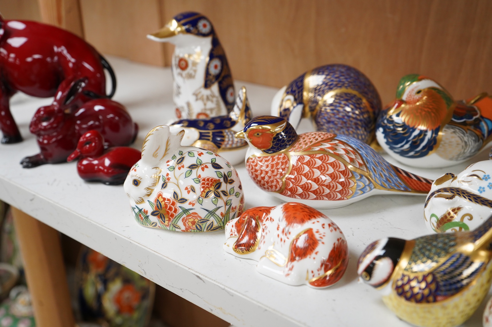 A collection of Royal Crown Derby Imari pattern paperweights, to include penguin and badger, together with three Doulton flambé animals, largest 19cm wide